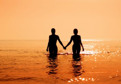 silhouette image of two bikini girls holding hands